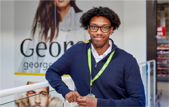 ASDA employee standing in the clothes-ware section of the supermarket and smiling. 