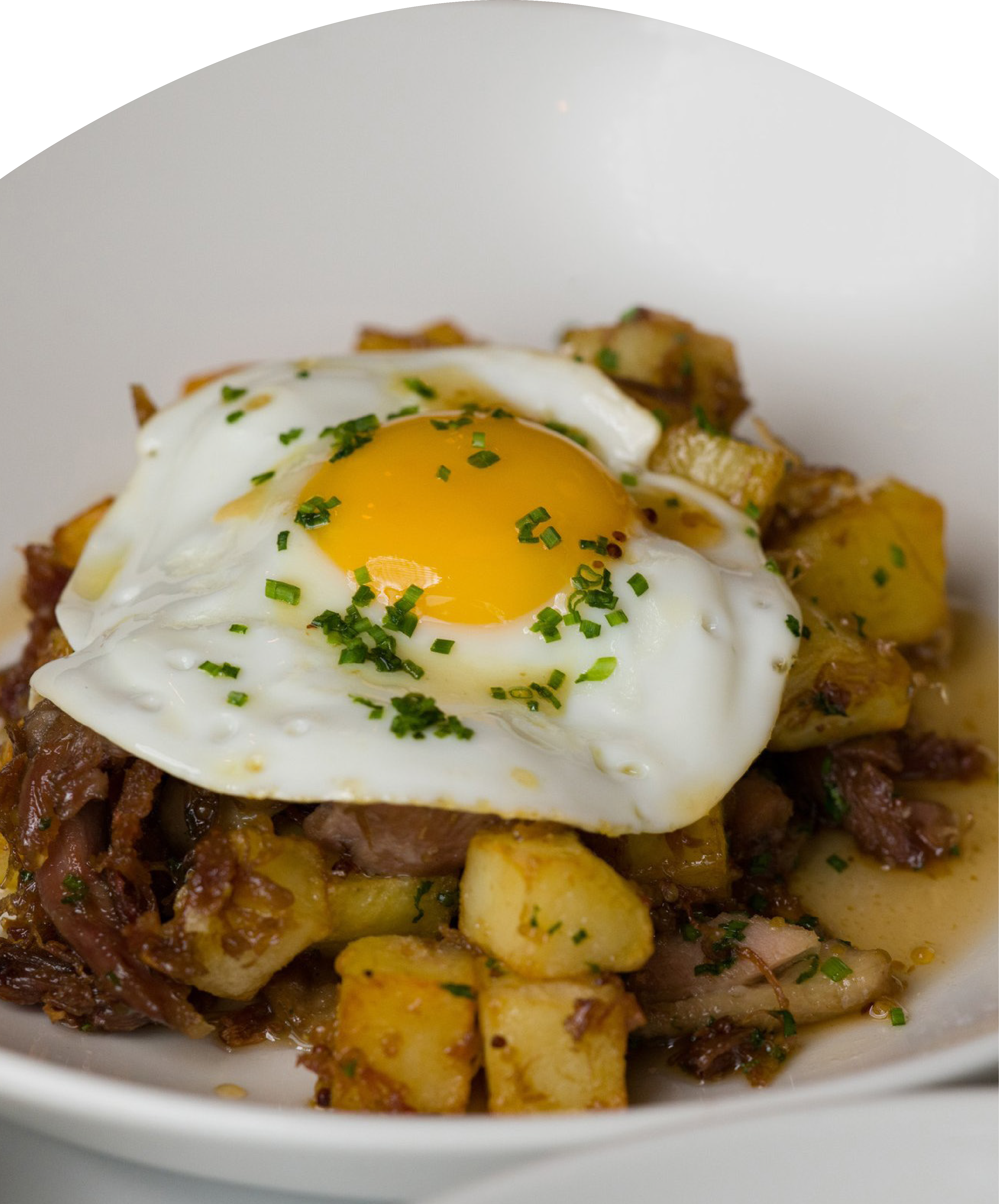 Fried cubed potatoes and shredded meat topped with a sunny-side-up egg garnished with chopped herbs.
