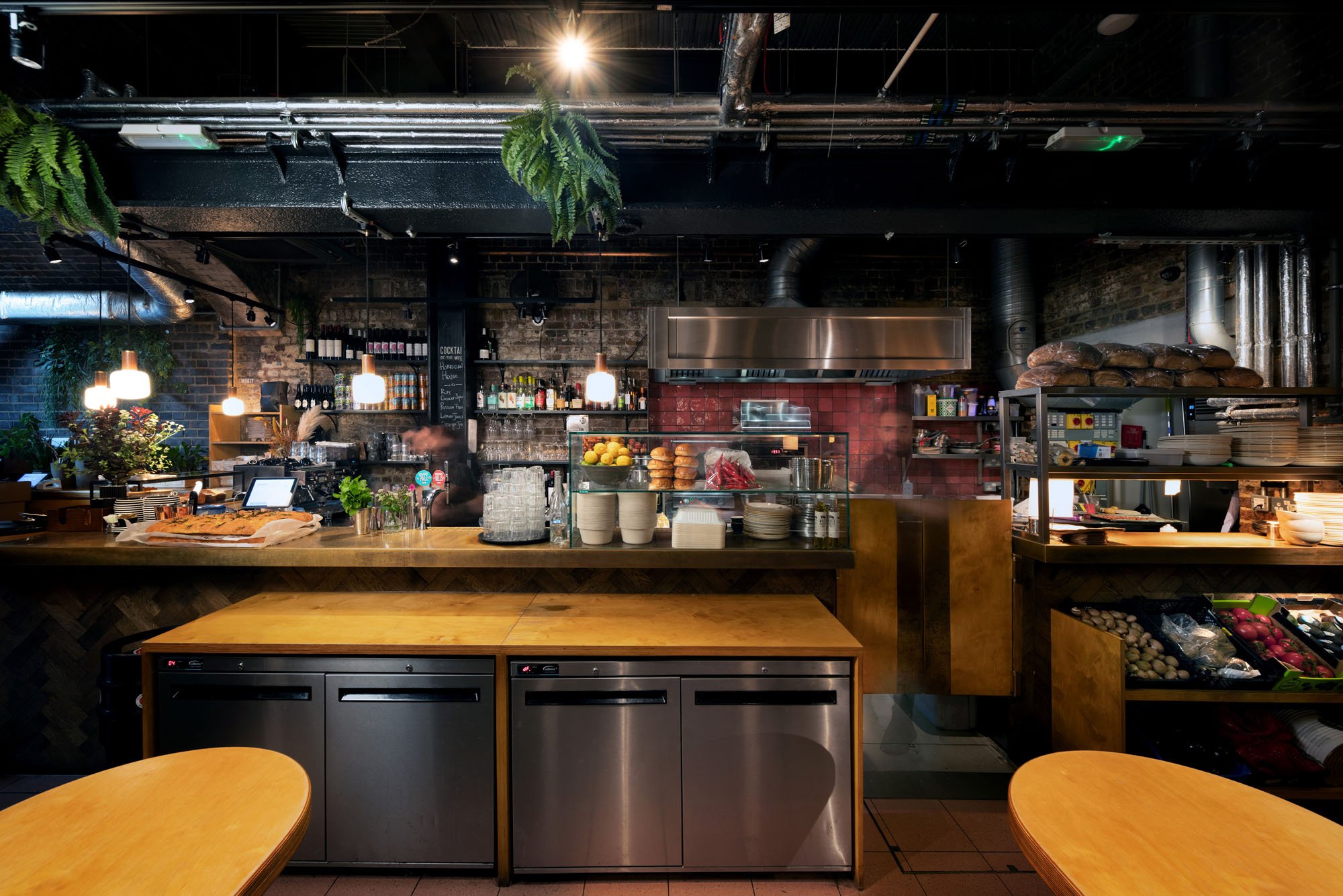 Modern cafe counter with hanging lights, bread, lemons, and a kitchen area.