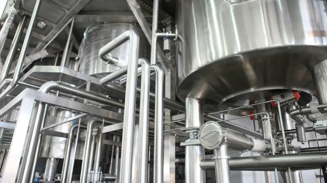 Stainless steel tanks and interconnected pipes in a modern industrial facility, showing precision engineering and clean manufacturing systems.