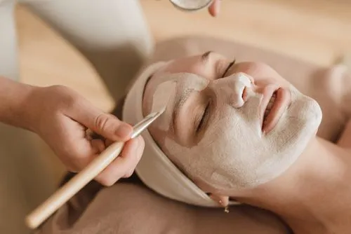 A woman getting a facial mask on her face.