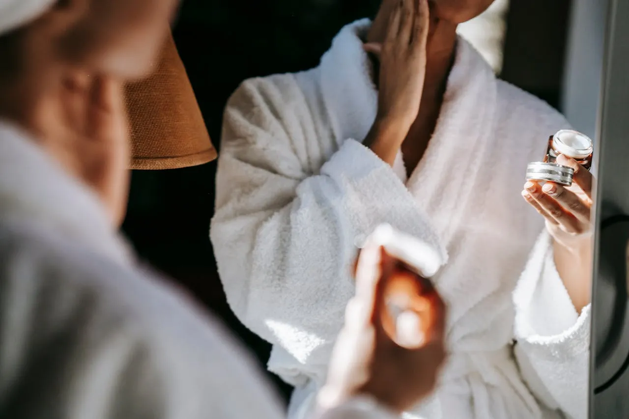 A woman in a white robe is brushing her teeth.