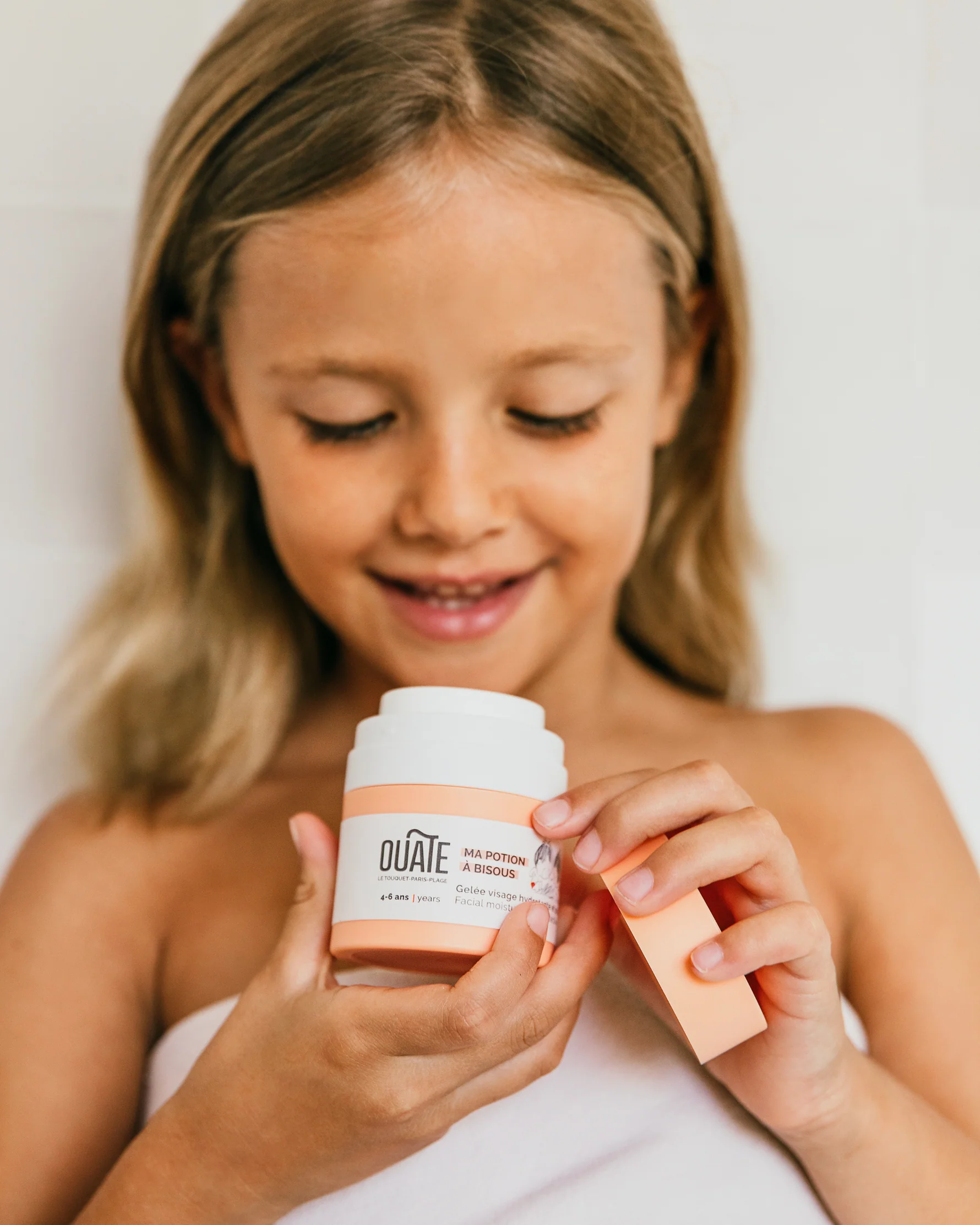 Enfant utilisant sa potion à bisous, une gelée visage hydratante d'Ouate Paris