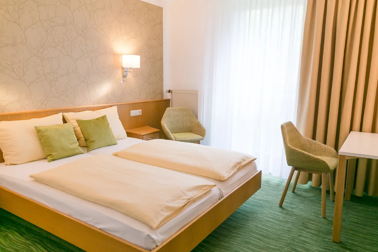 Modern eingerichtetes Hotelzimmer mit Doppelbett, Stuhl und großem Fenster.