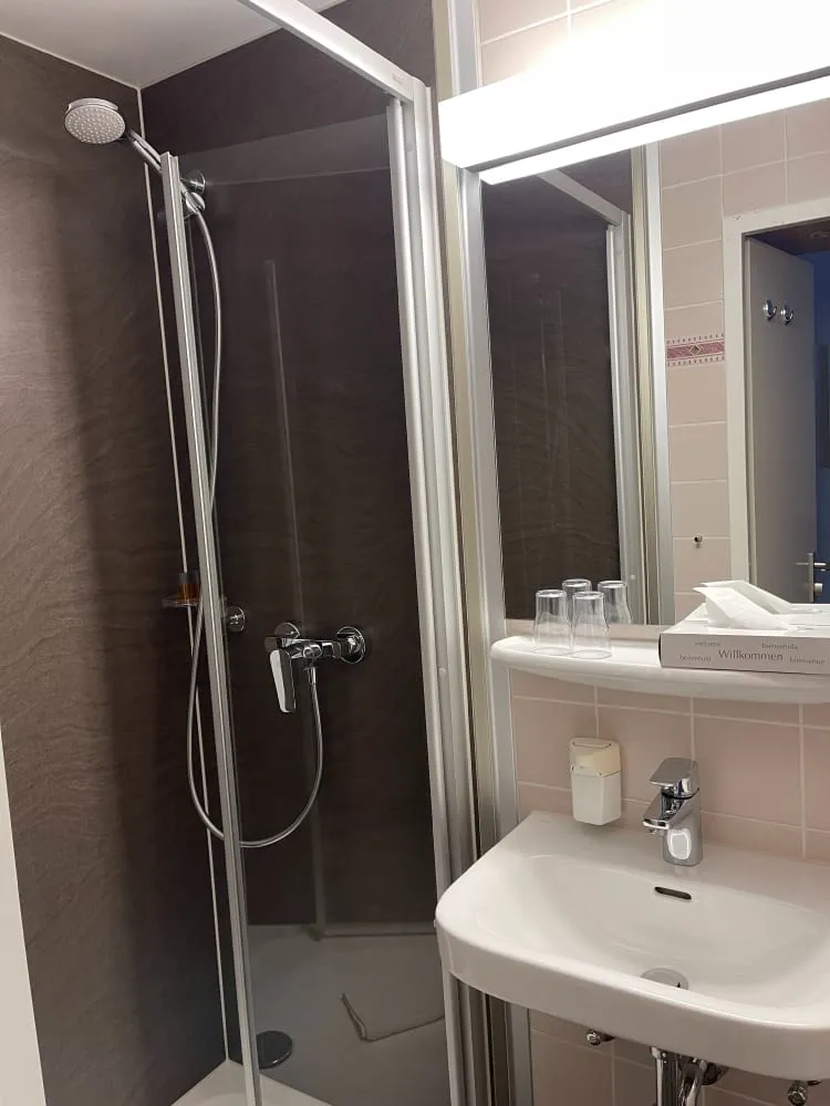 Modernes Hotelbad mit Dusche, Waschbecken und Spiegel.