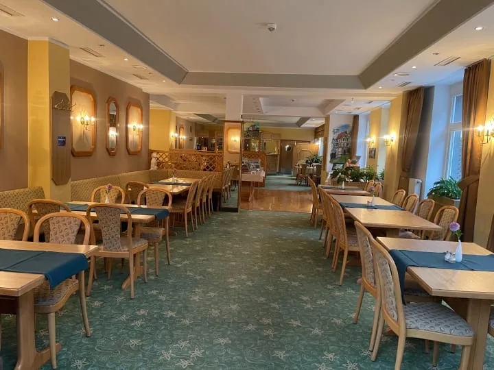 Geräumiges Restaurant mit vielen gedeckten Tischen und warm beleuchteter Atmosphäre.