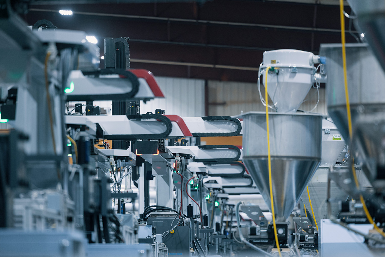 Factory filled with robotic assisted plastic injection molding machines.