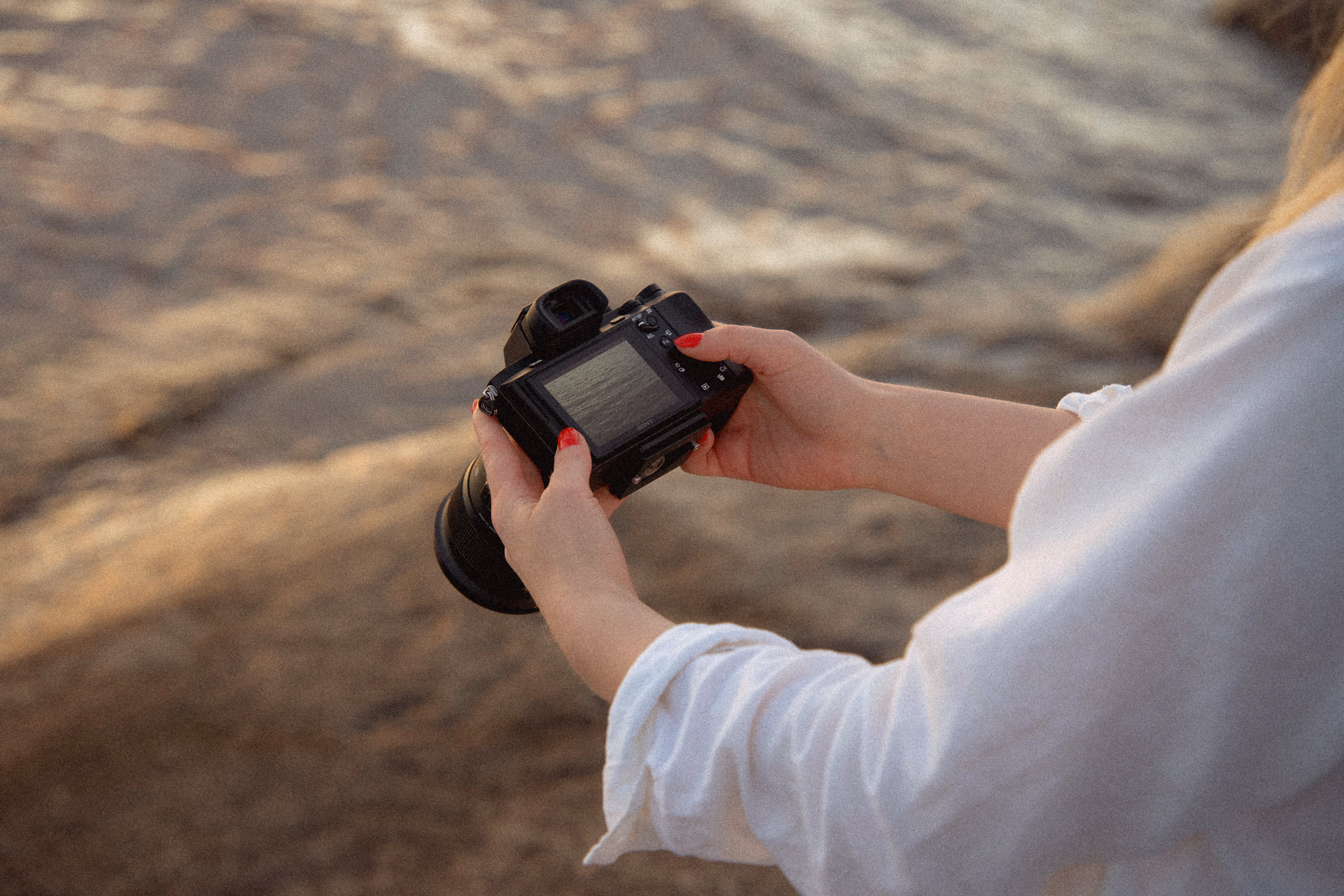 Kädet pitelevät kameraa järvimaisemassa kuvastaen Stooren aitoa sisältömarkkinointia ja yritykselle räätälöityä kuvapankkia