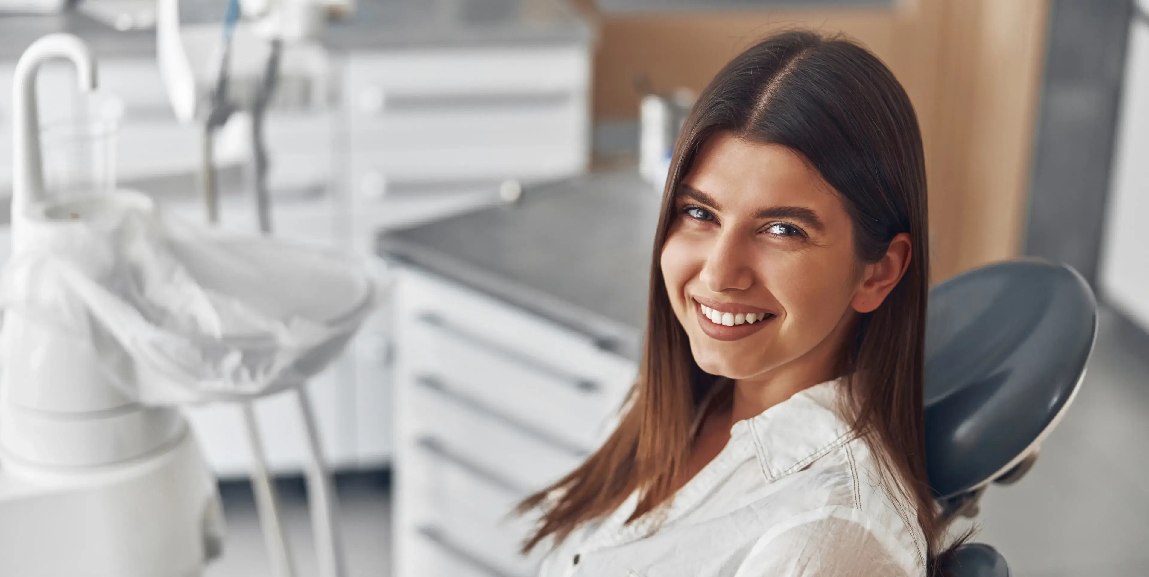 A woman sitting in a dentist chair smiling.