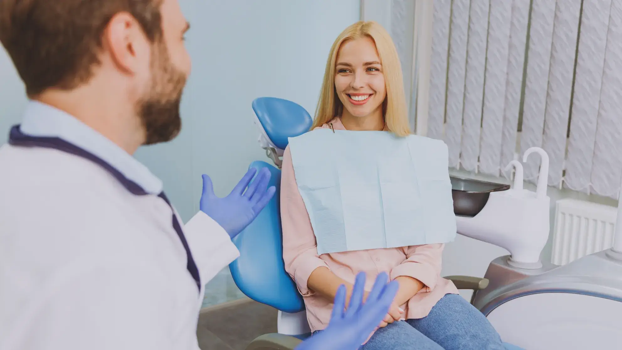 A woman sitting in a dental chair with a blue mask on her face.