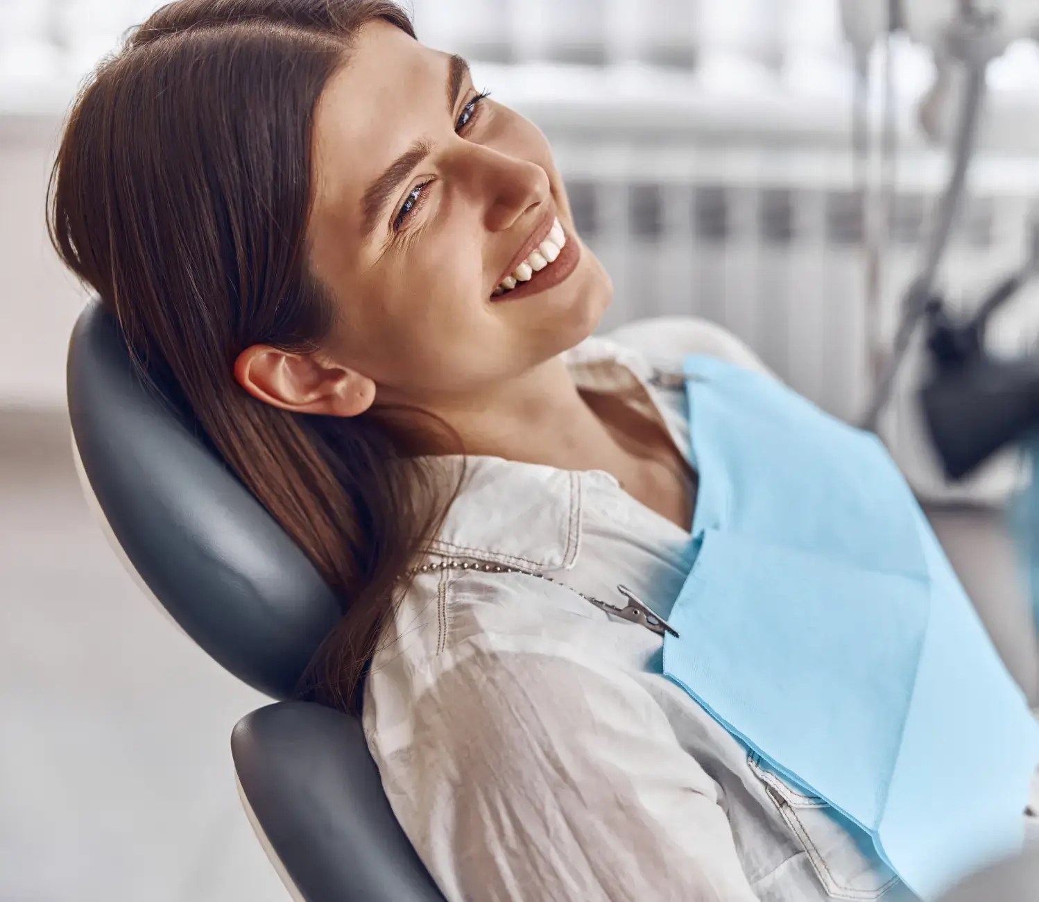 A woman sitting in a dentist chair smiling.
