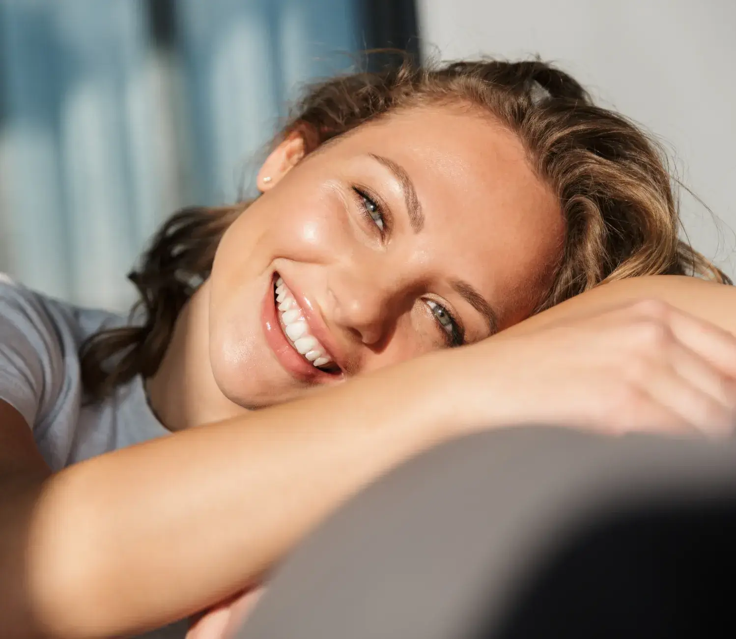 A woman is smiling and hugging her arm.