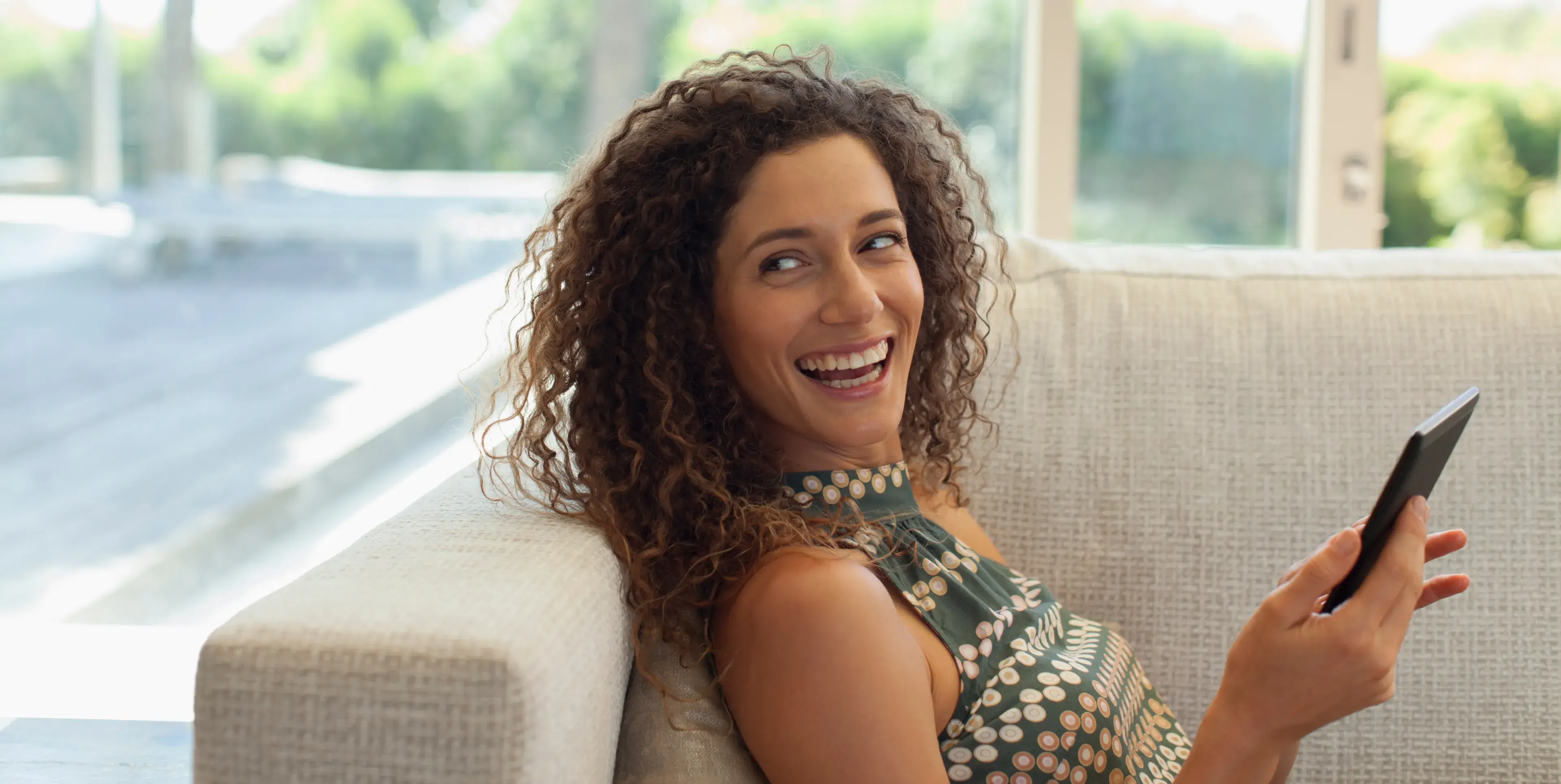 A woman sitting on a couch holding a cell phone.