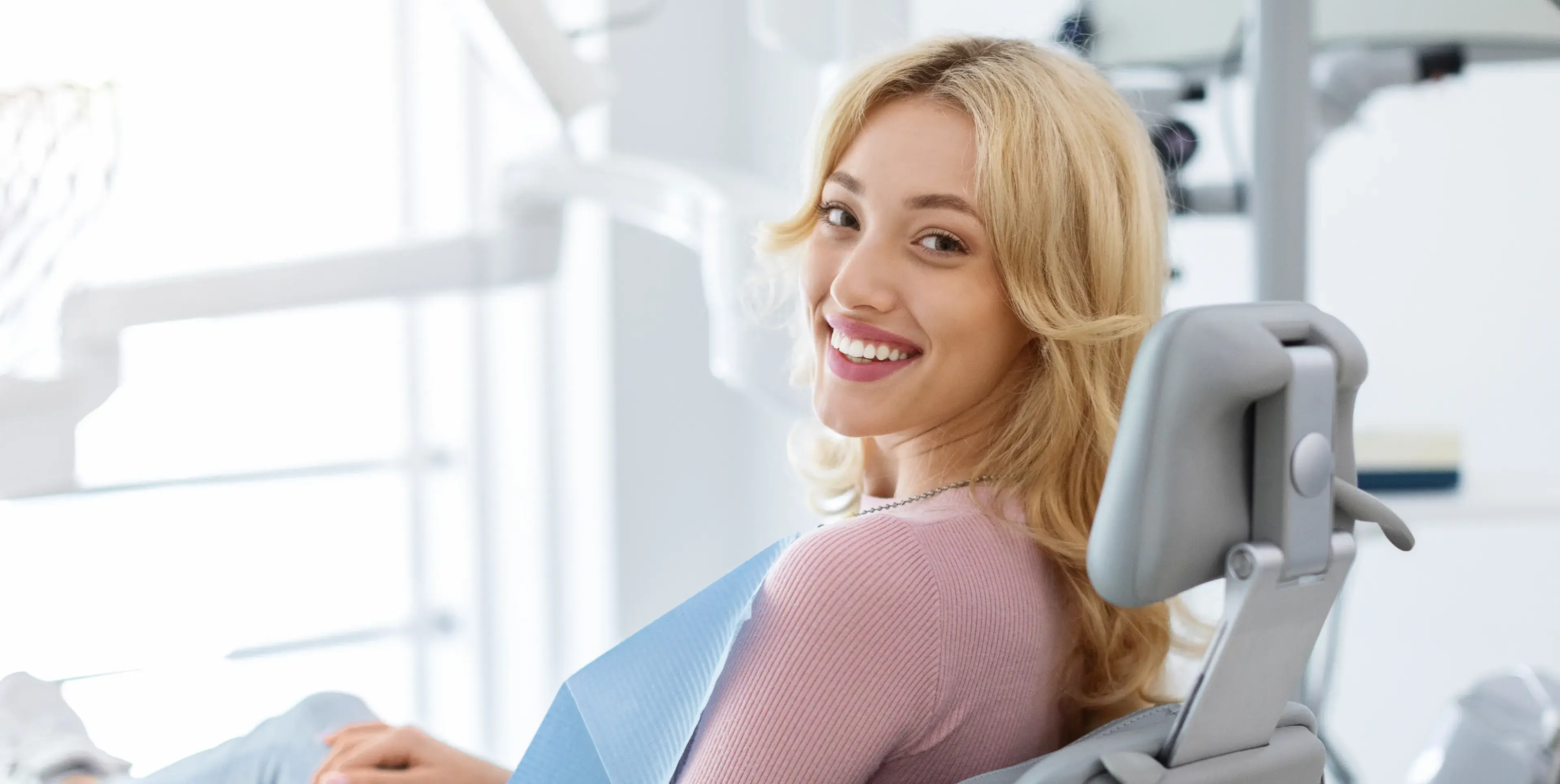 A woman sitting in a dental chair smiling.