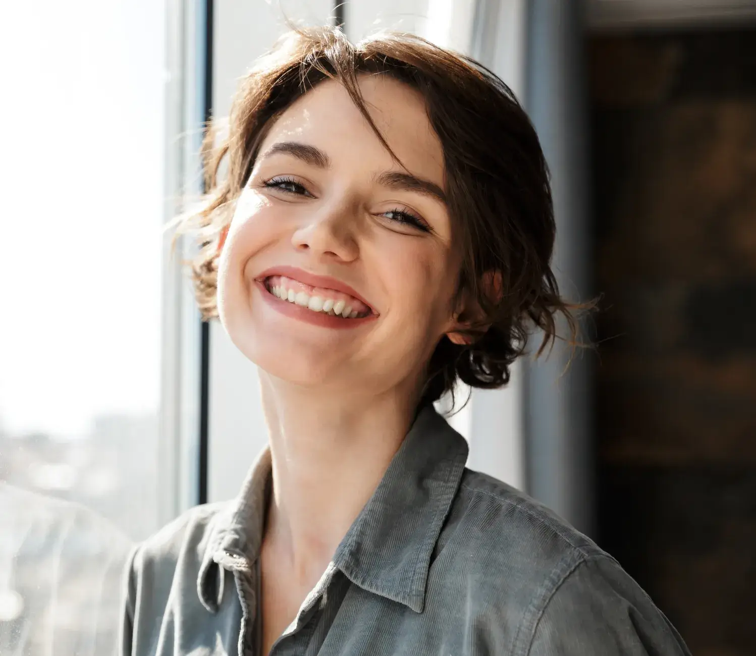 A woman smiling and looking out a window.