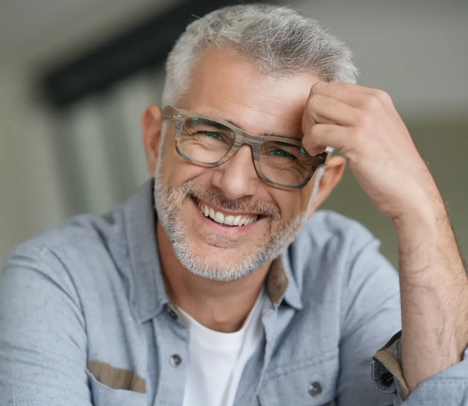 A smiling man with glasses and a blue shirt.