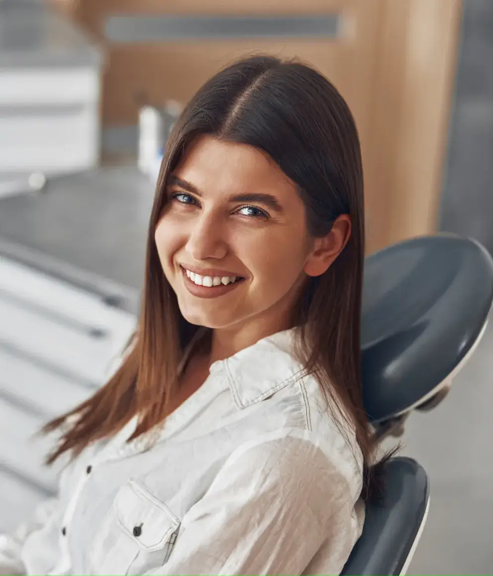 A smiling woman sitting in a dental chair.