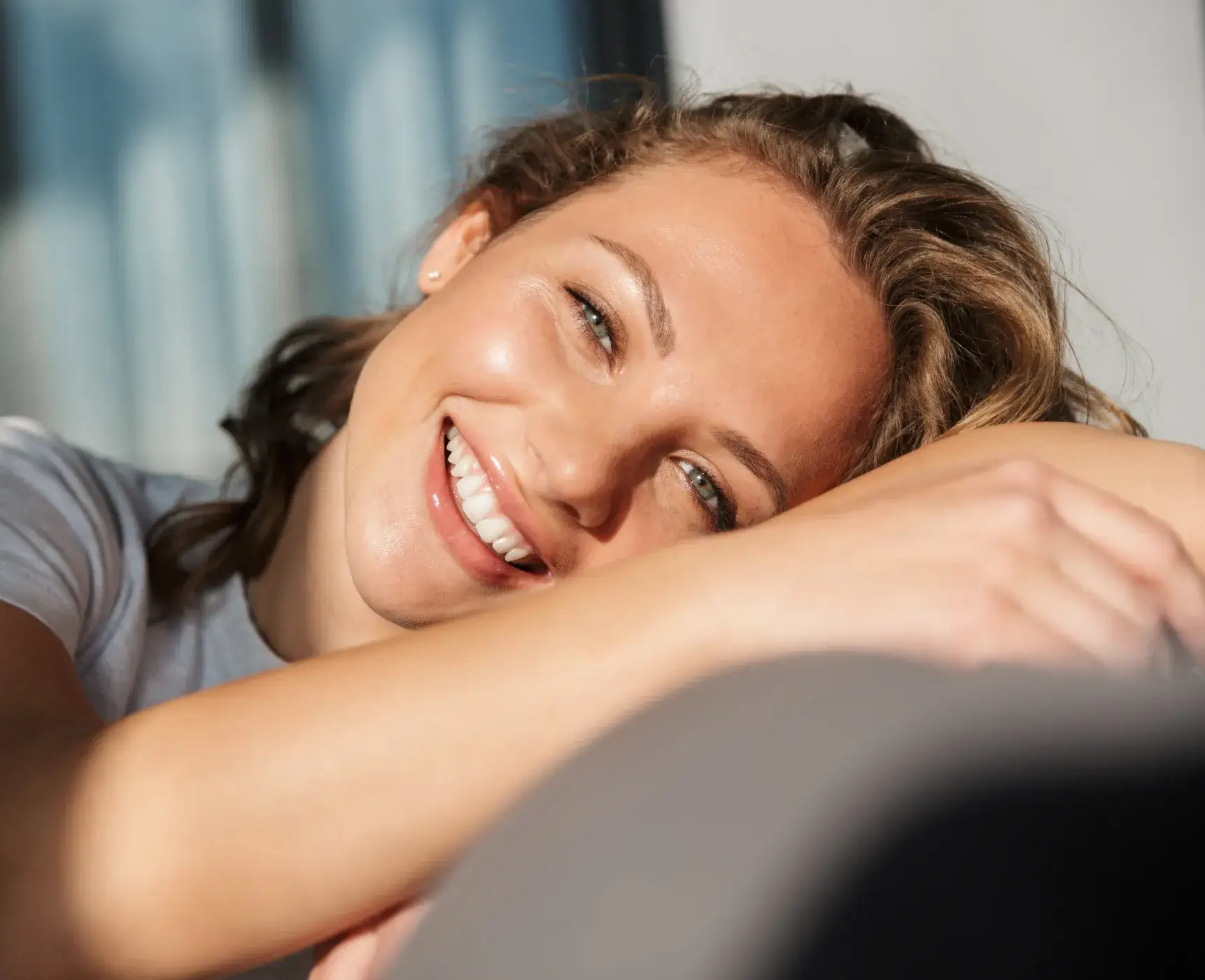 A woman smiling and leaning on a couch.