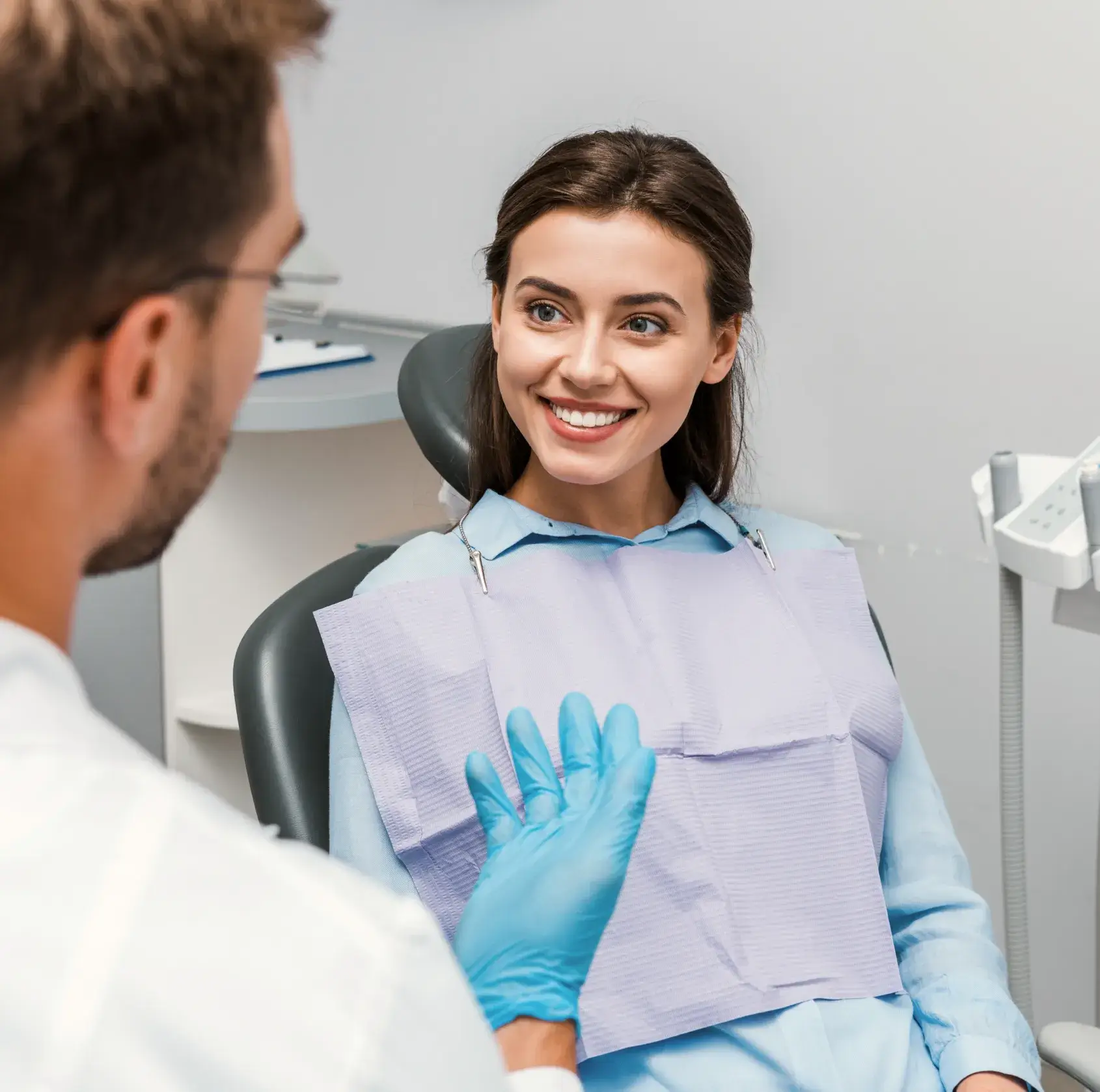 A woman sitting in a dentist chair with gloves on.