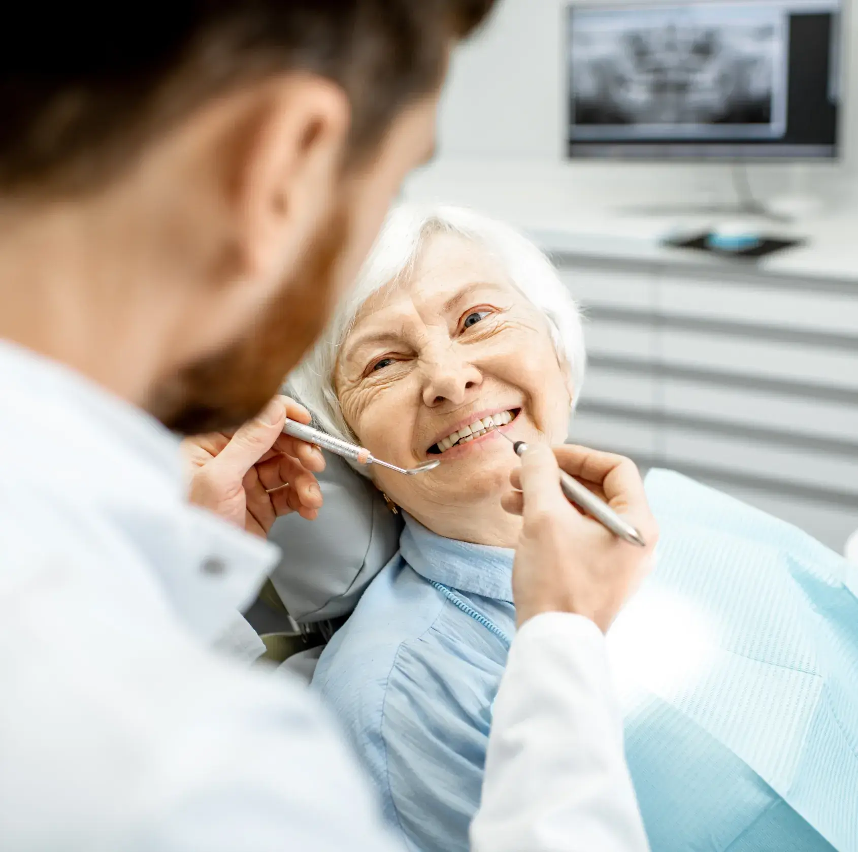 A woman sitting in a dentist chair with a toothbrush in her mouth.
