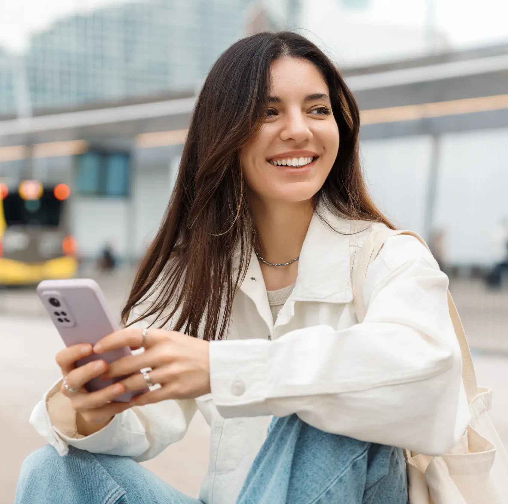A woman sitting on the ground holding a cell phone.