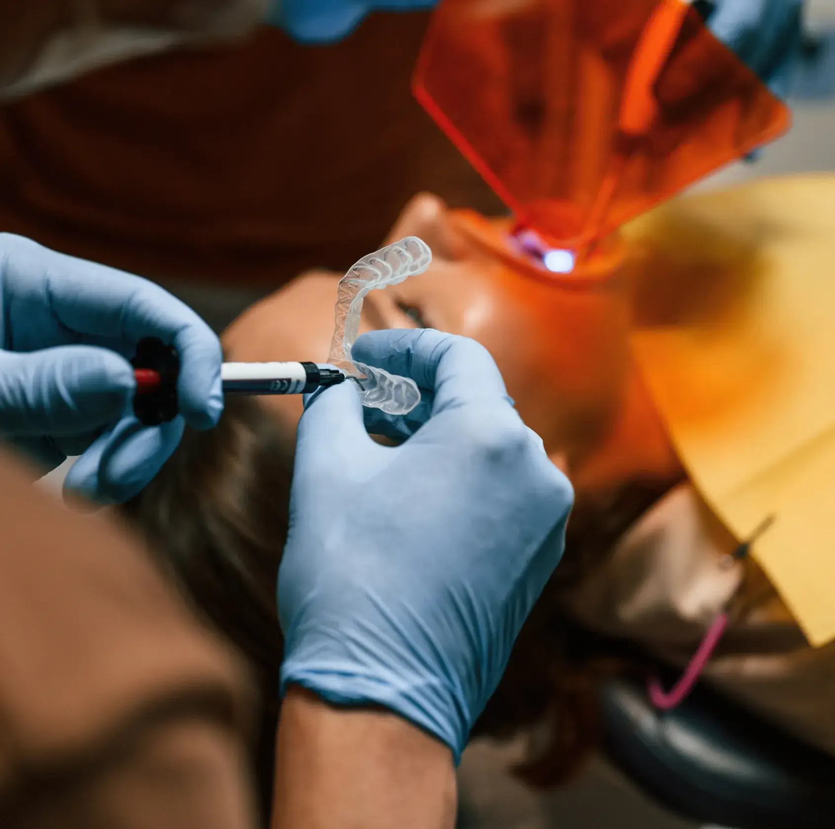 A person in a dentist's chair with a toothbrush in their hand.
