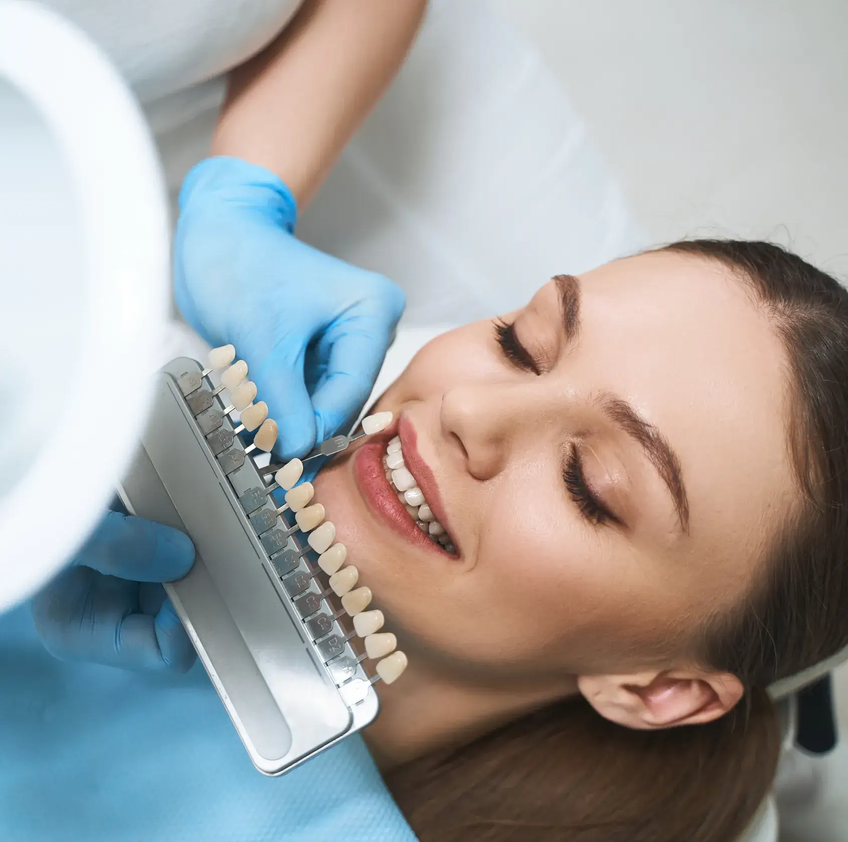 A woman getting her teeth brushed by a dentist.