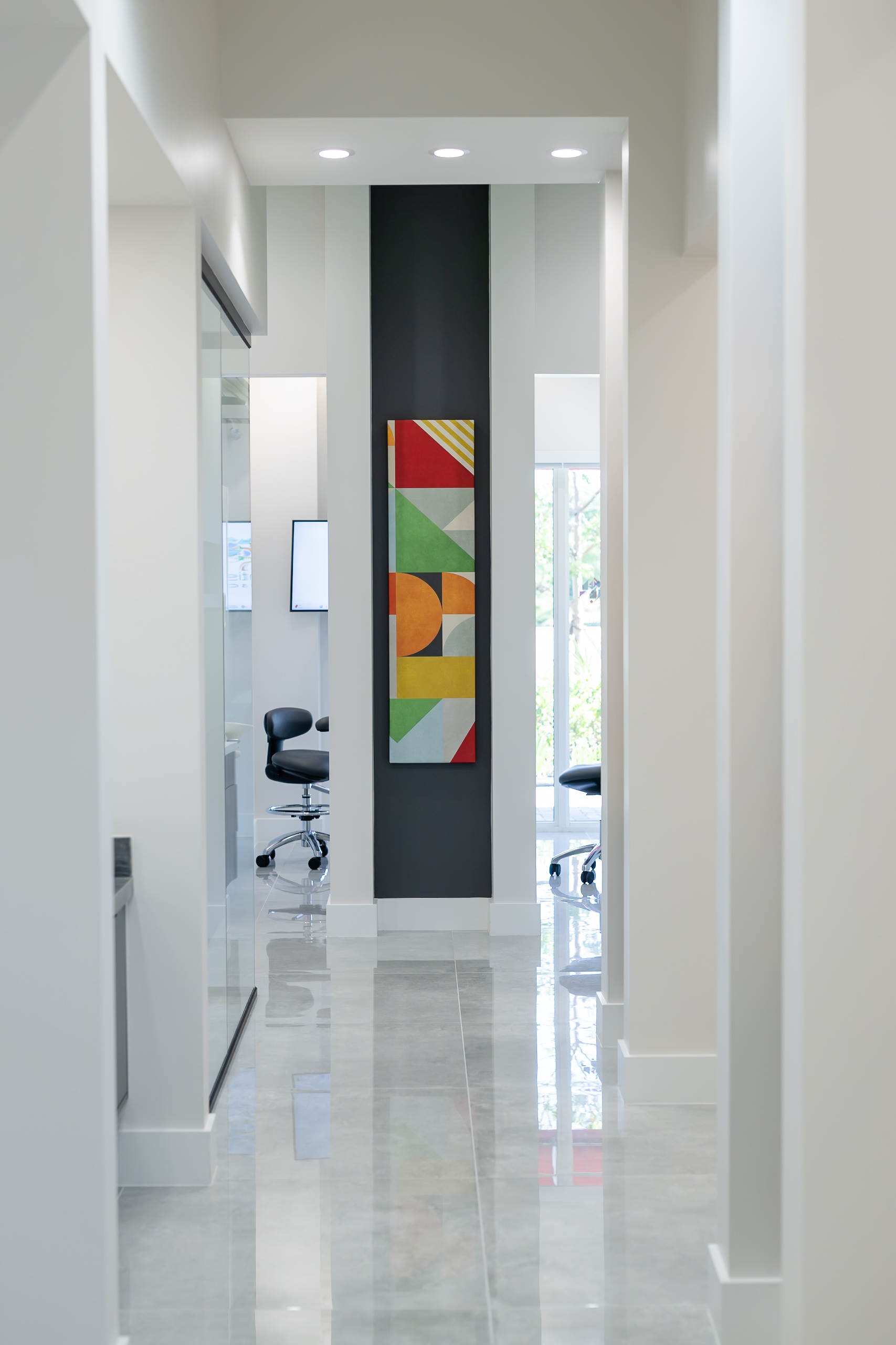 Modern interior hallway at Gen2 Dentistry in Davie, Florida with dental chair and ceiling mounted TV.