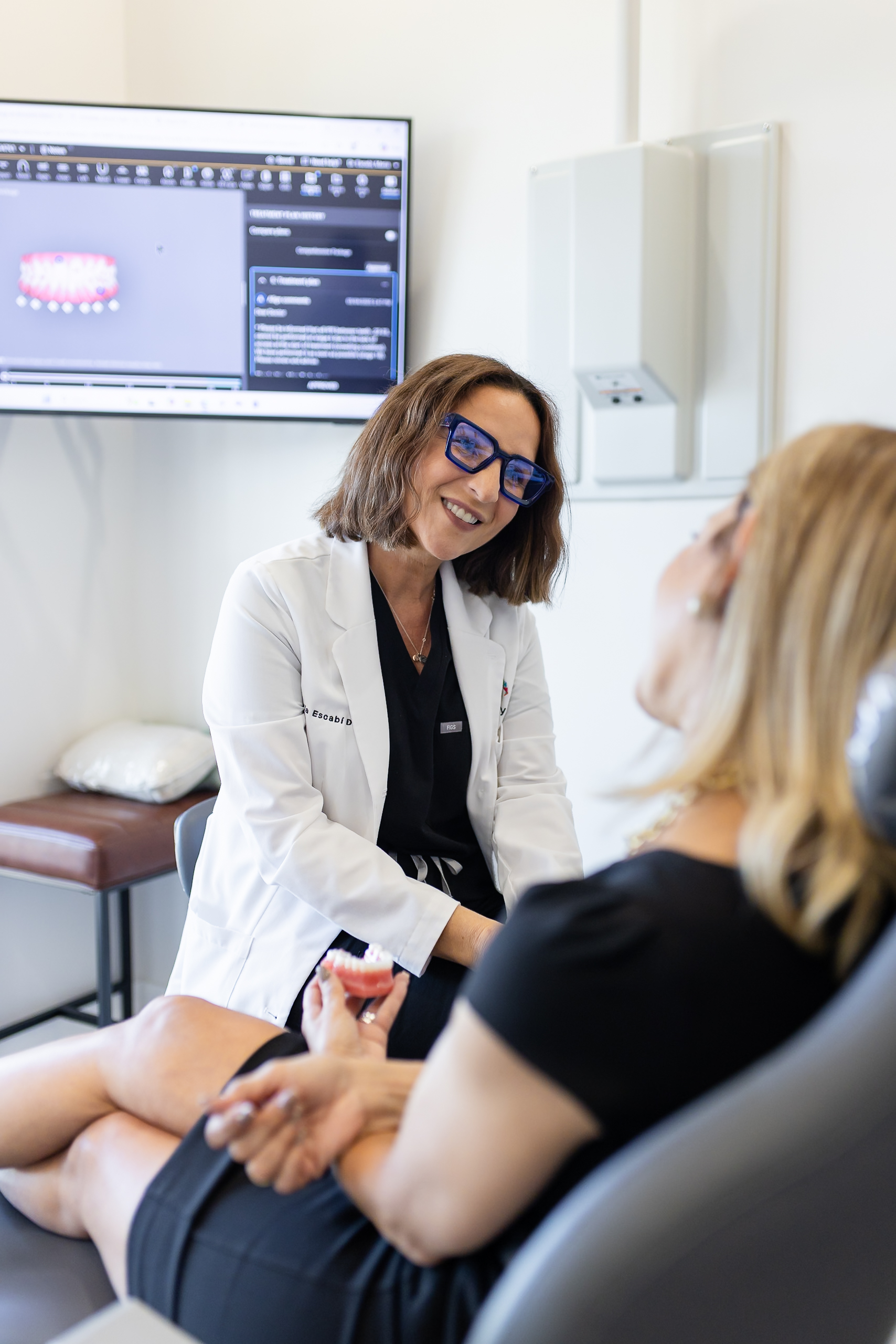 Dentist at Gen2 Dentistry in Davie, Florida, consulting with a patient while holding a dental model.