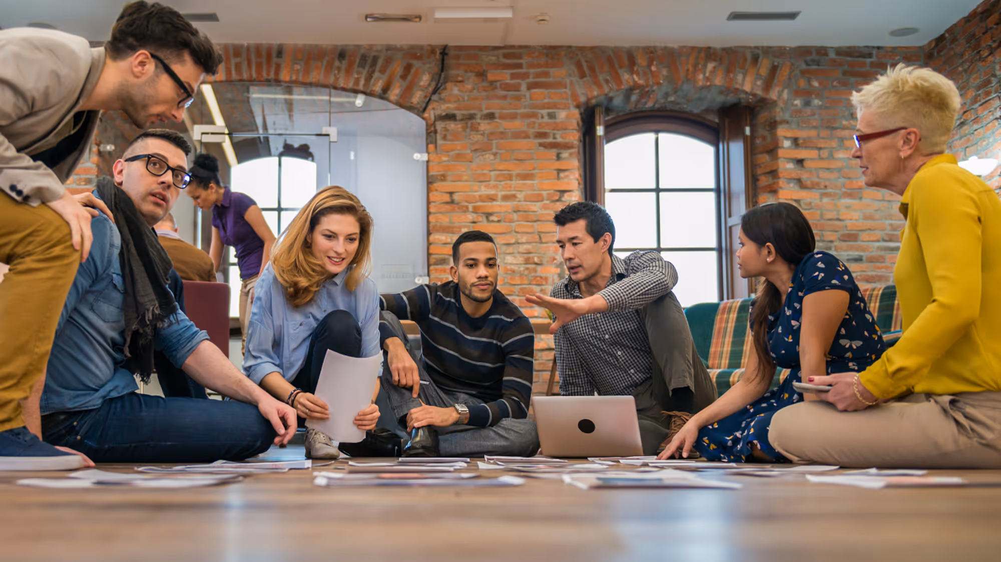 A diverse group of young adults sitting in a circle on the floor during a group discussion session.