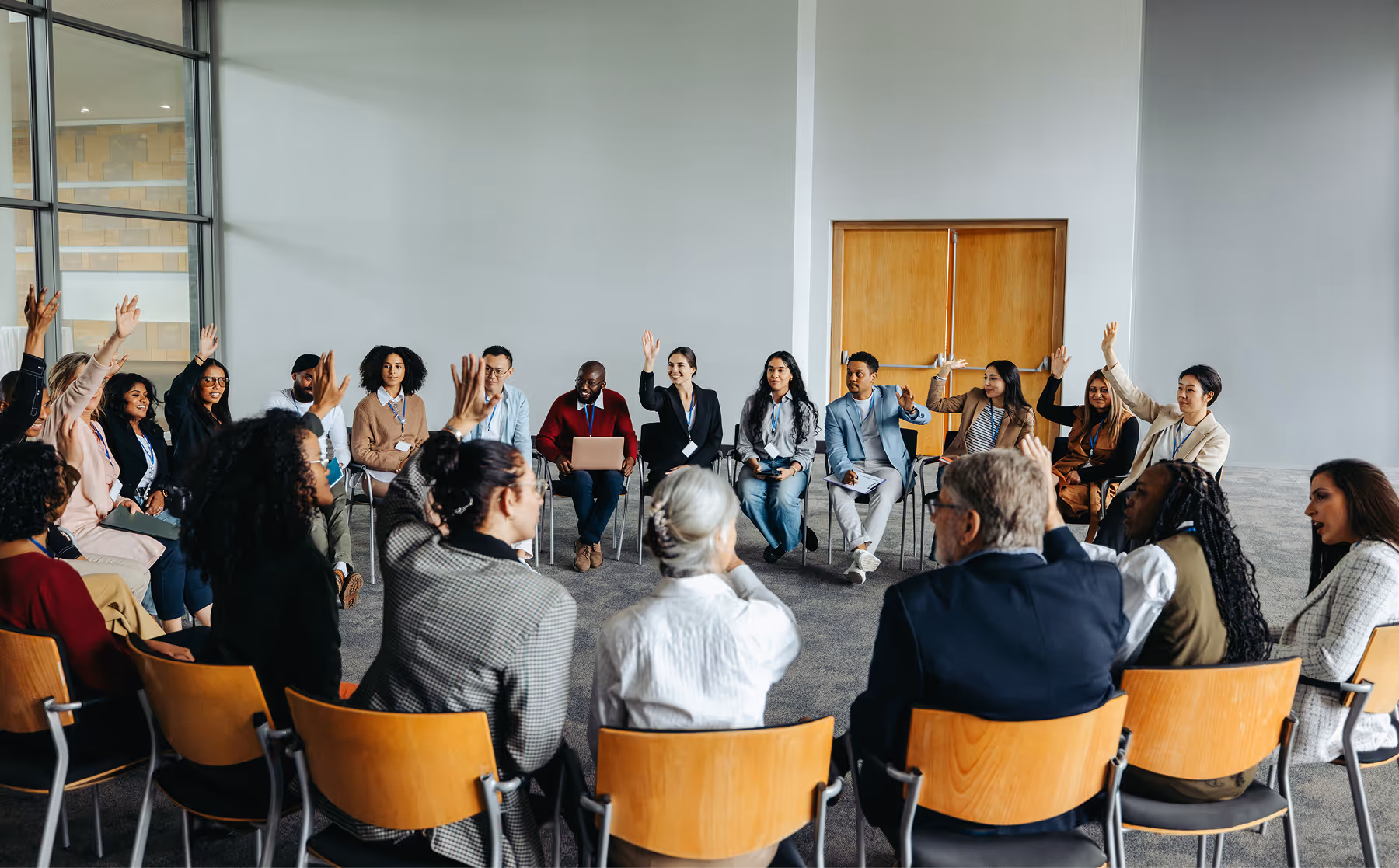 A large group of adults seated in a circle participating in a facilitated group session.