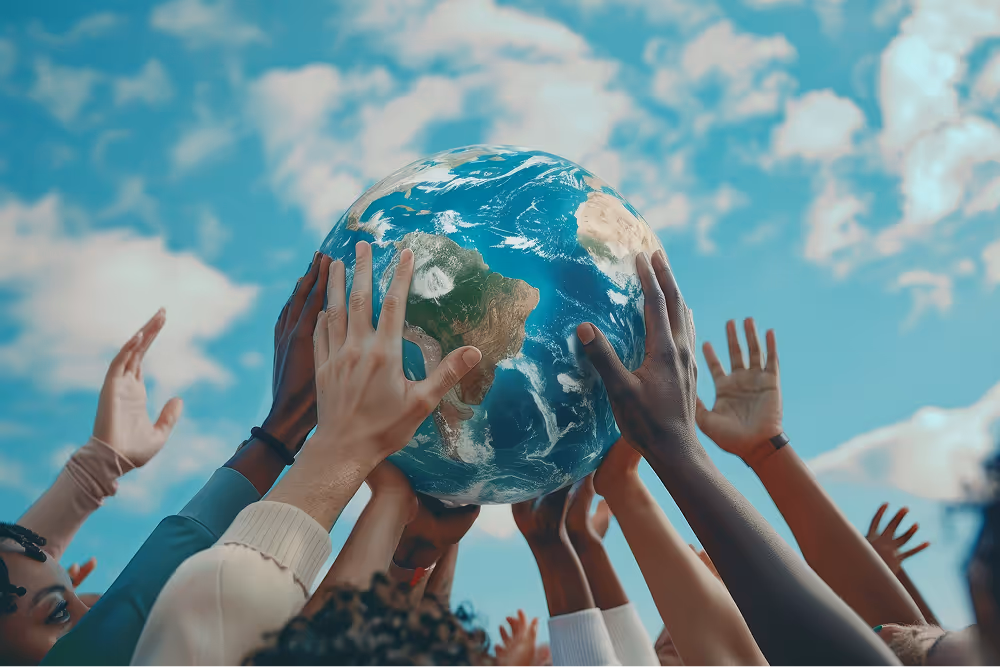 A group of diverse hands lifting a globe toward the sky to symbolize unity and global connection.