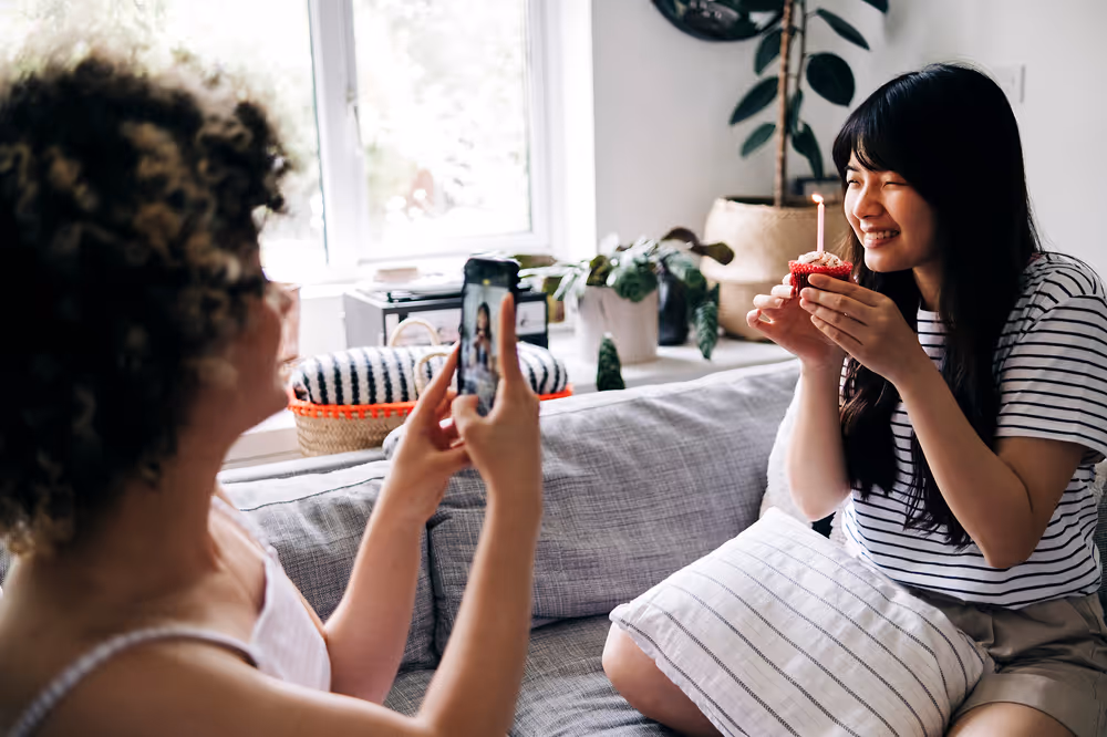 Two friends taking photos and celebrating a birthday.