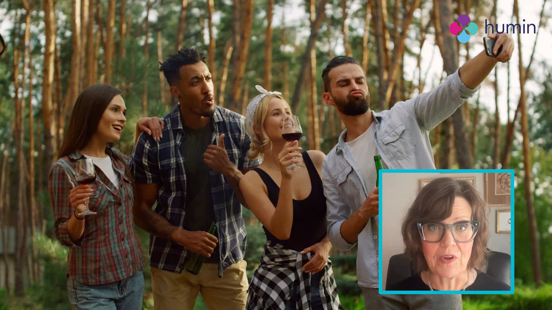 Four friends outdoors in a forest taking a selfie, two holding wine glasses and two holding beer bottles, with an inset of a woman speaking on a video call.