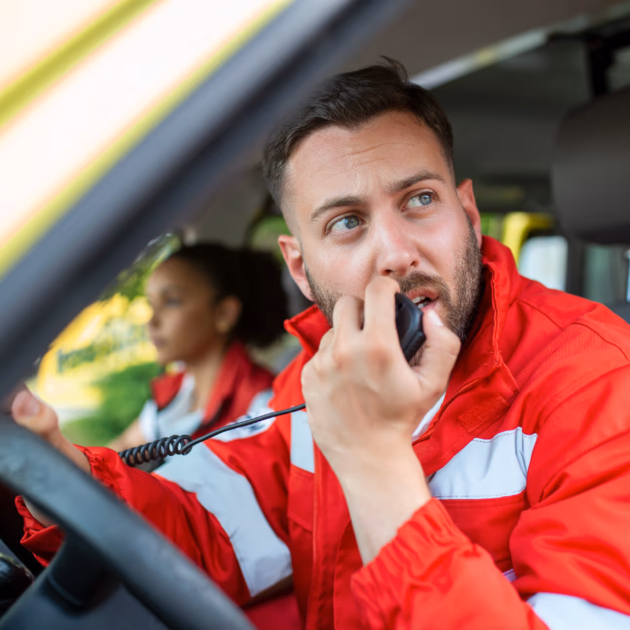 A man sitting in a car talking on a cell phone.