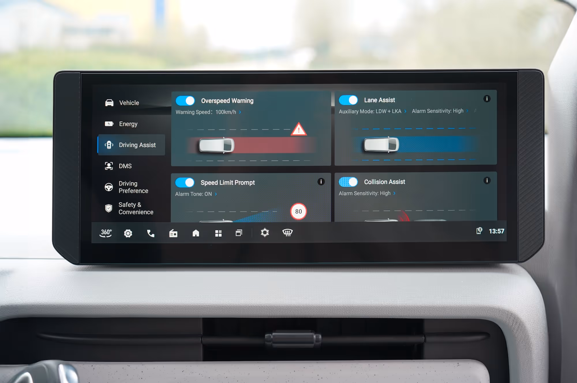 Car dashboard touchscreen showing driving assist settings including overspeed warning, lane assist, speed limit prompt, and collision assist all activated.