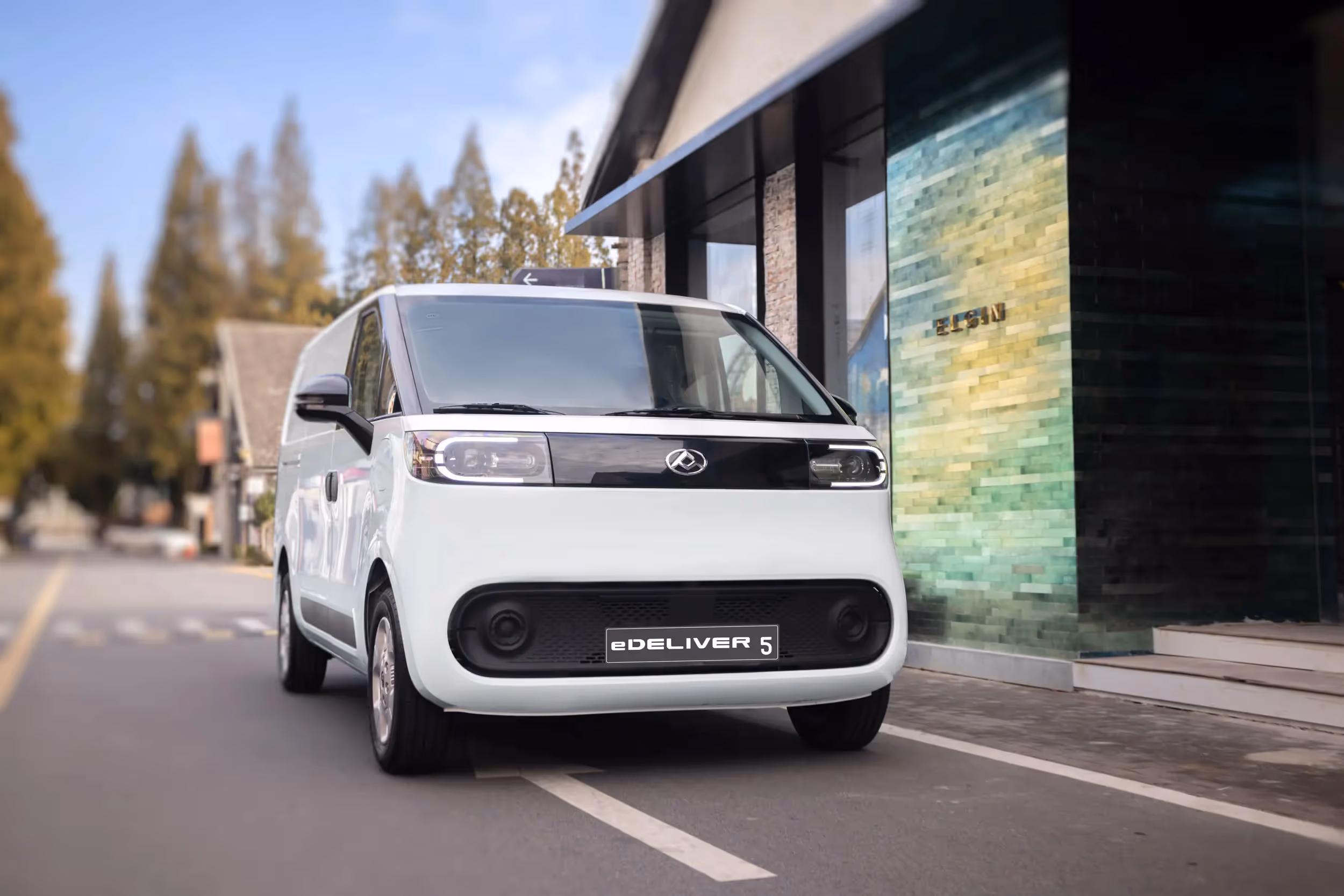 White eDeliver 5 electric delivery van parked on a street next to a building with green tiles.