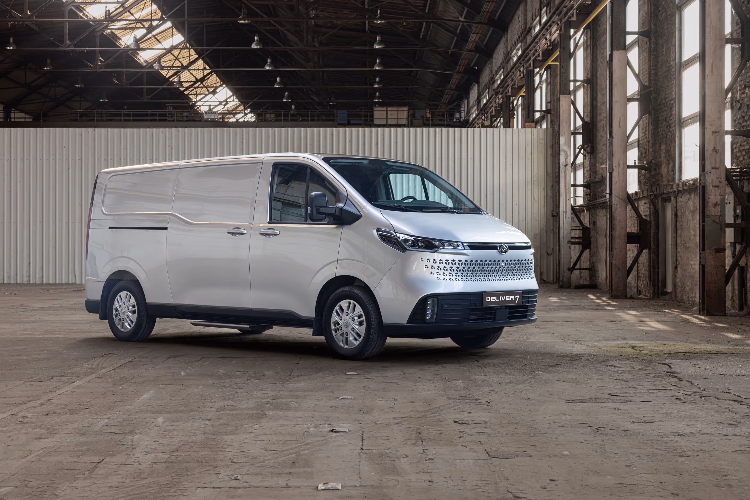 Silver Deliver 7 cargo van parked inside a large industrial warehouse with high windows and metal roof.