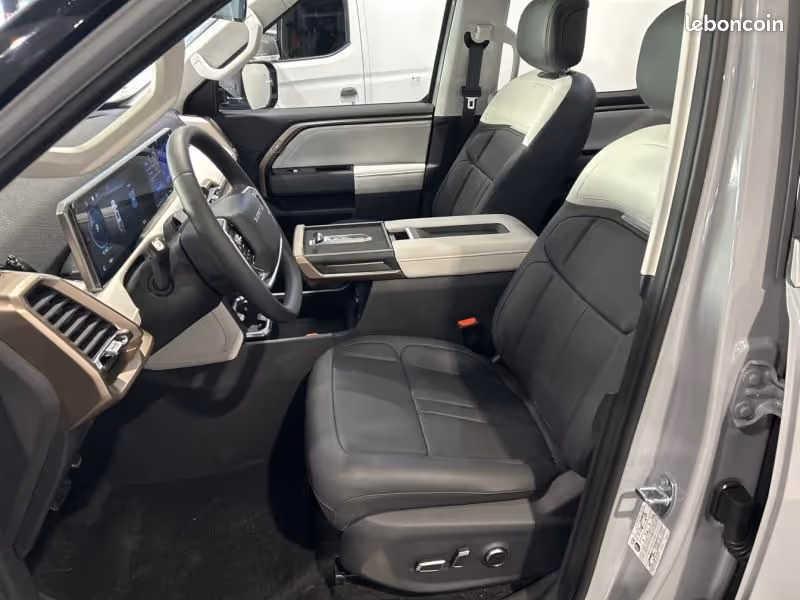 Interior front seats and dashboard of a modern vehicle with black and white leather upholstery and a digital dashboard.