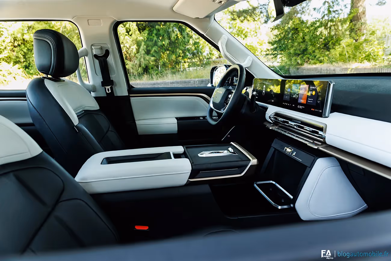Modern car interior featuring black and white leather seats, a large horizontal touchscreen dashboard, and a center console with a gear selector.