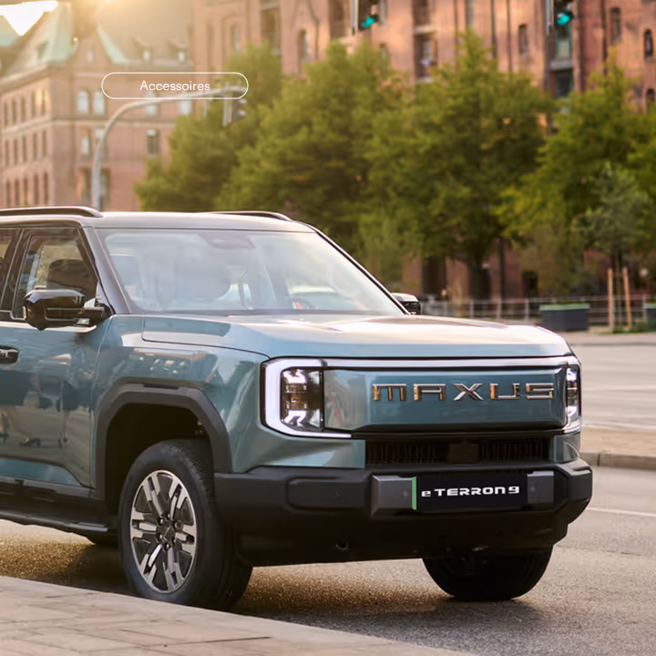 Green Maxus eTerron 9 electric SUV parked on a city street near trees and buildings.