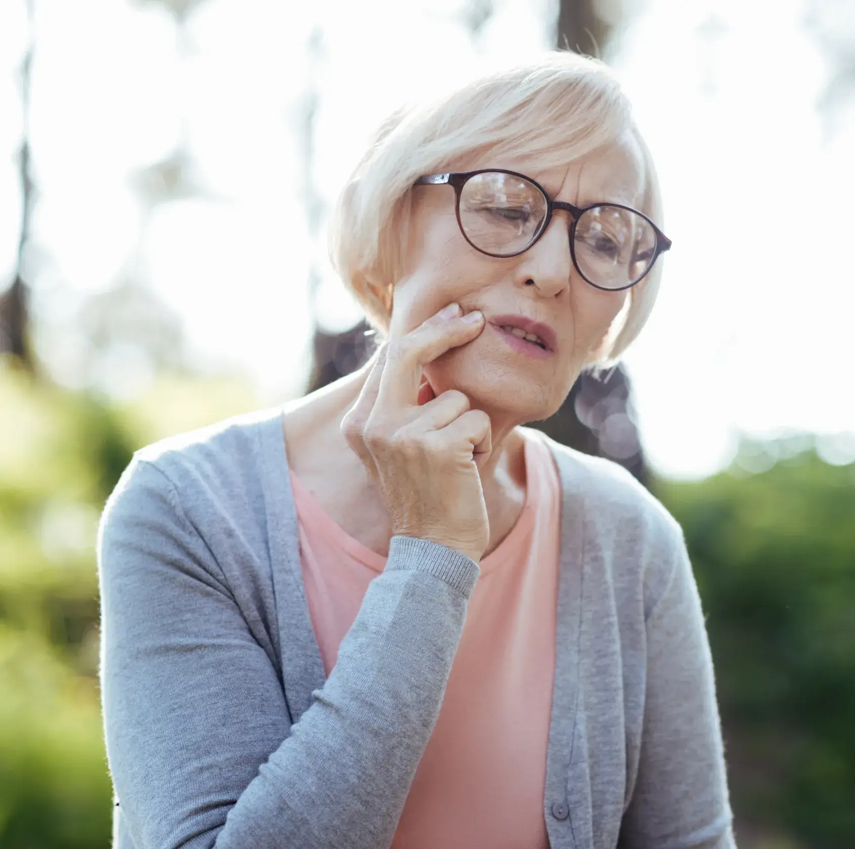 An older woman wearing glasses and a pink shirt.