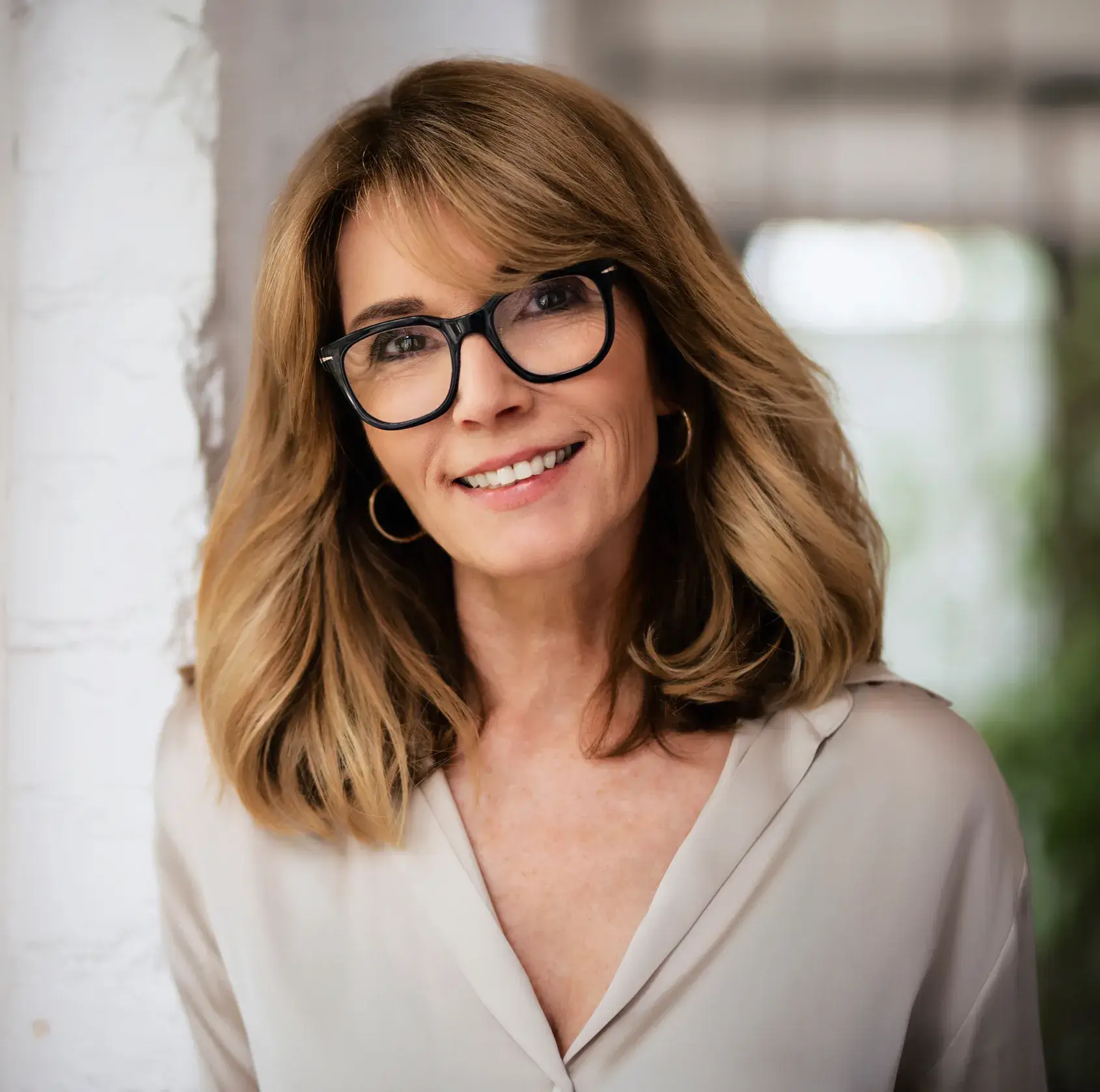 A woman with glasses smiling for the camera.