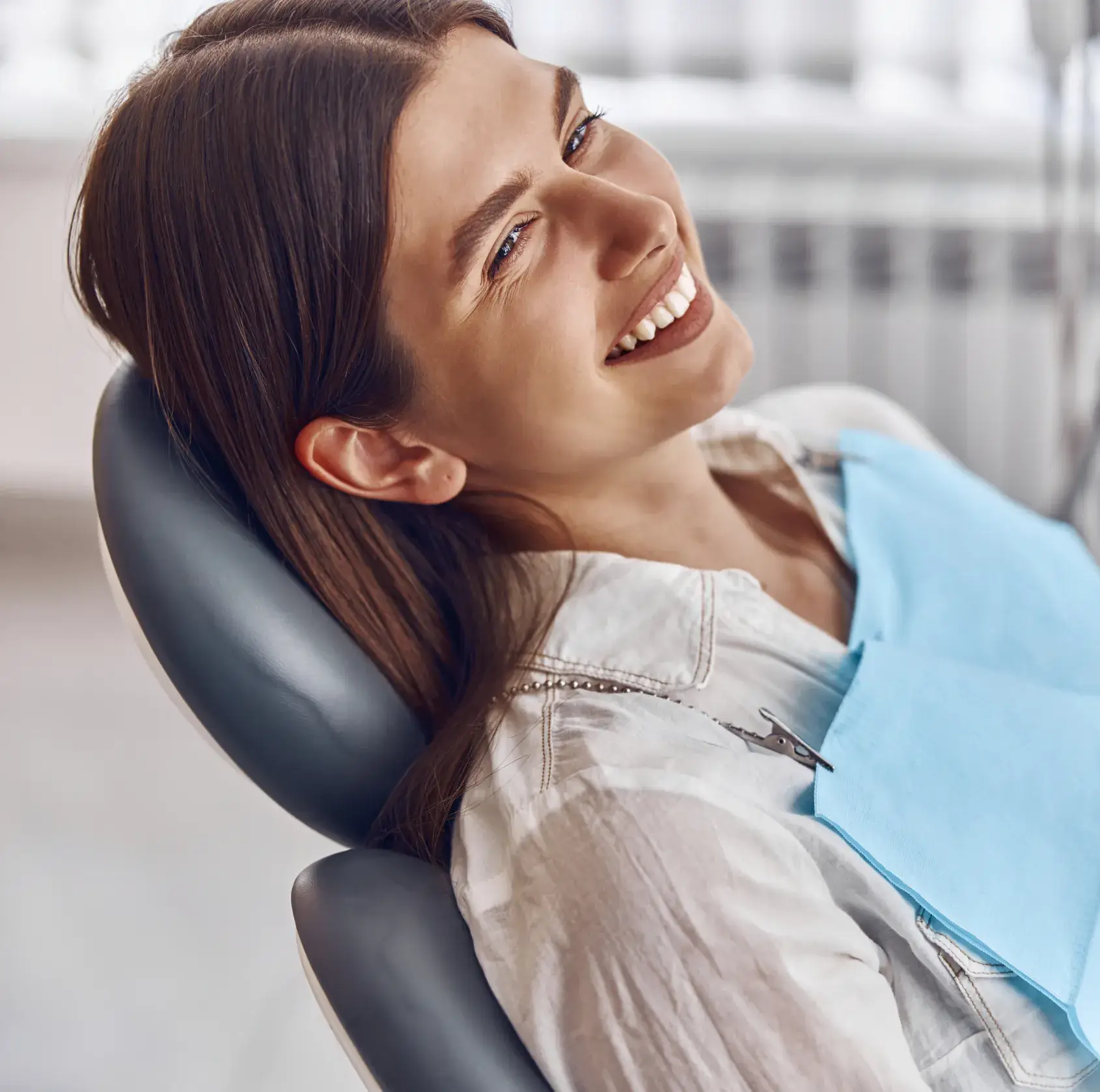 A woman sitting in a dentist chair smiling.
