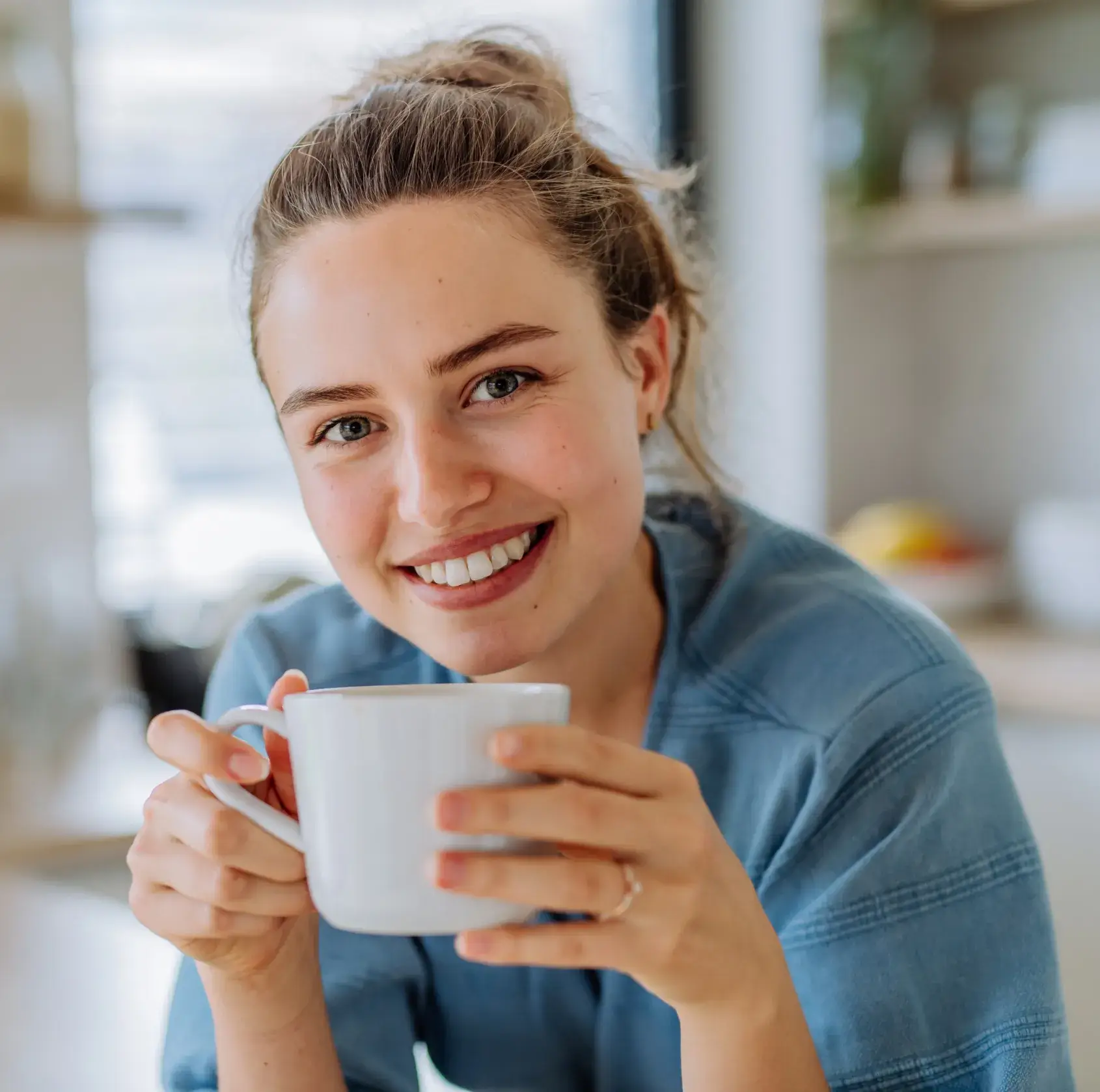 A smiling woman holding a cup of coffee.