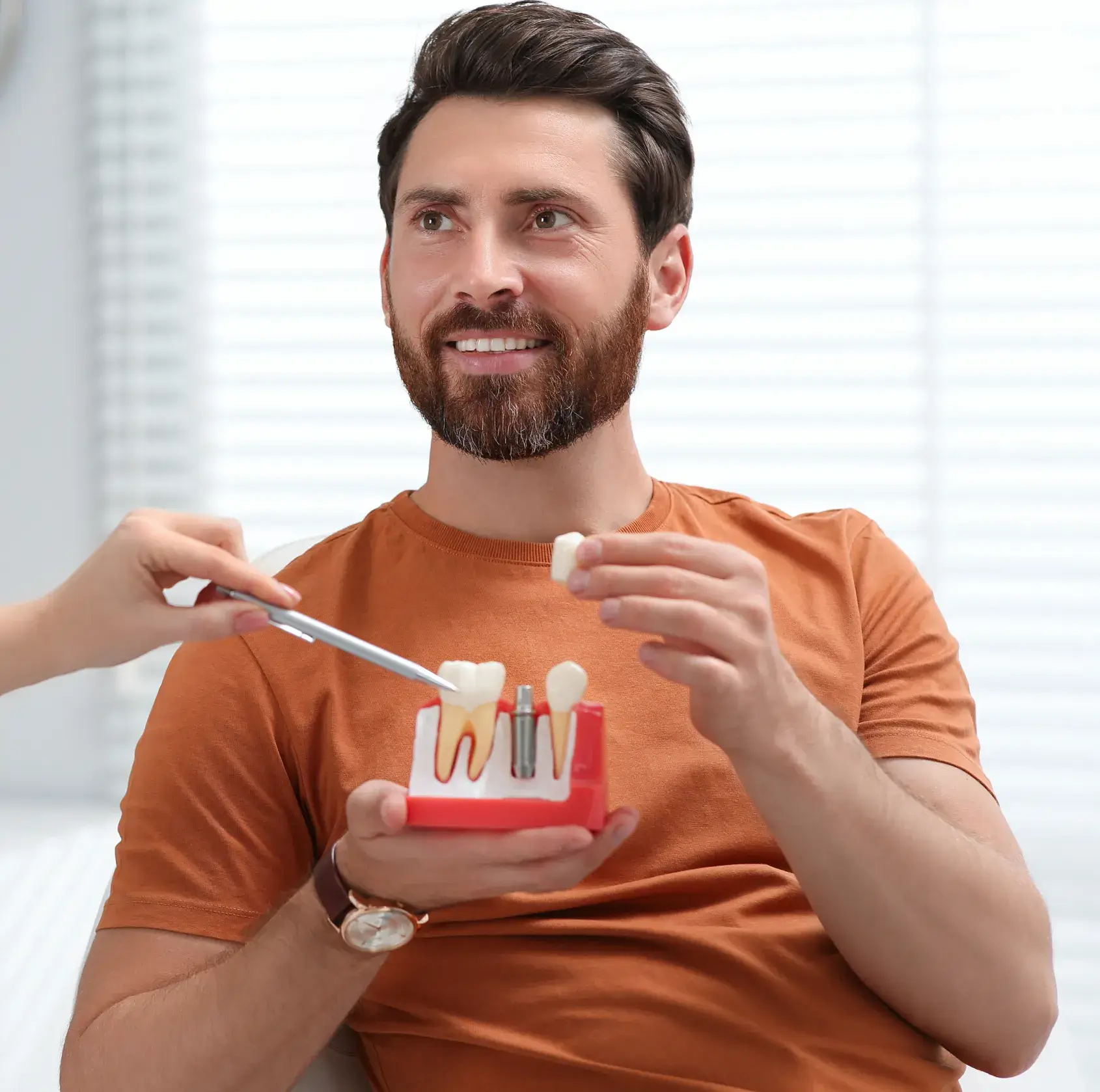 A man holding a toothbrush and a model of a tooth.