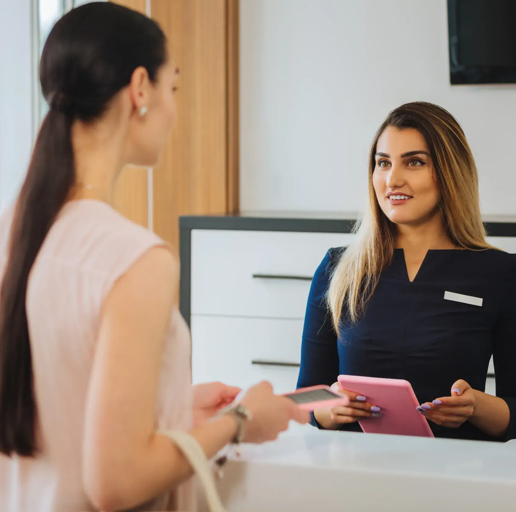 Two women sitting at a desk with a tablet.