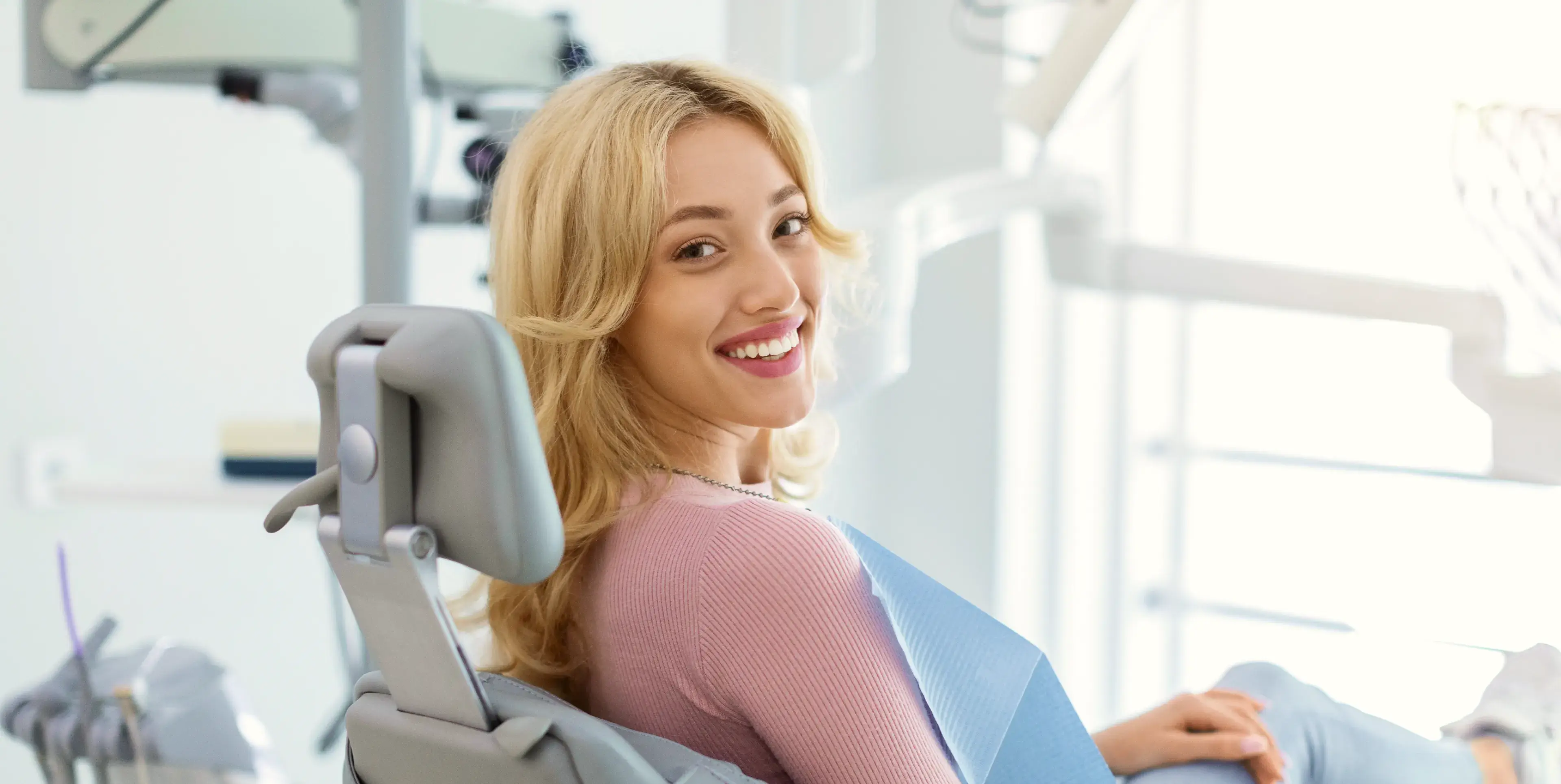 A woman sitting in a dental chair smiling.