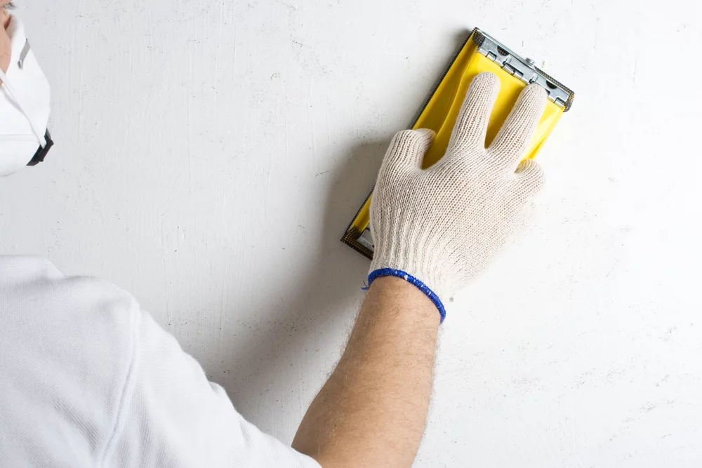 man prepping a wall for painting