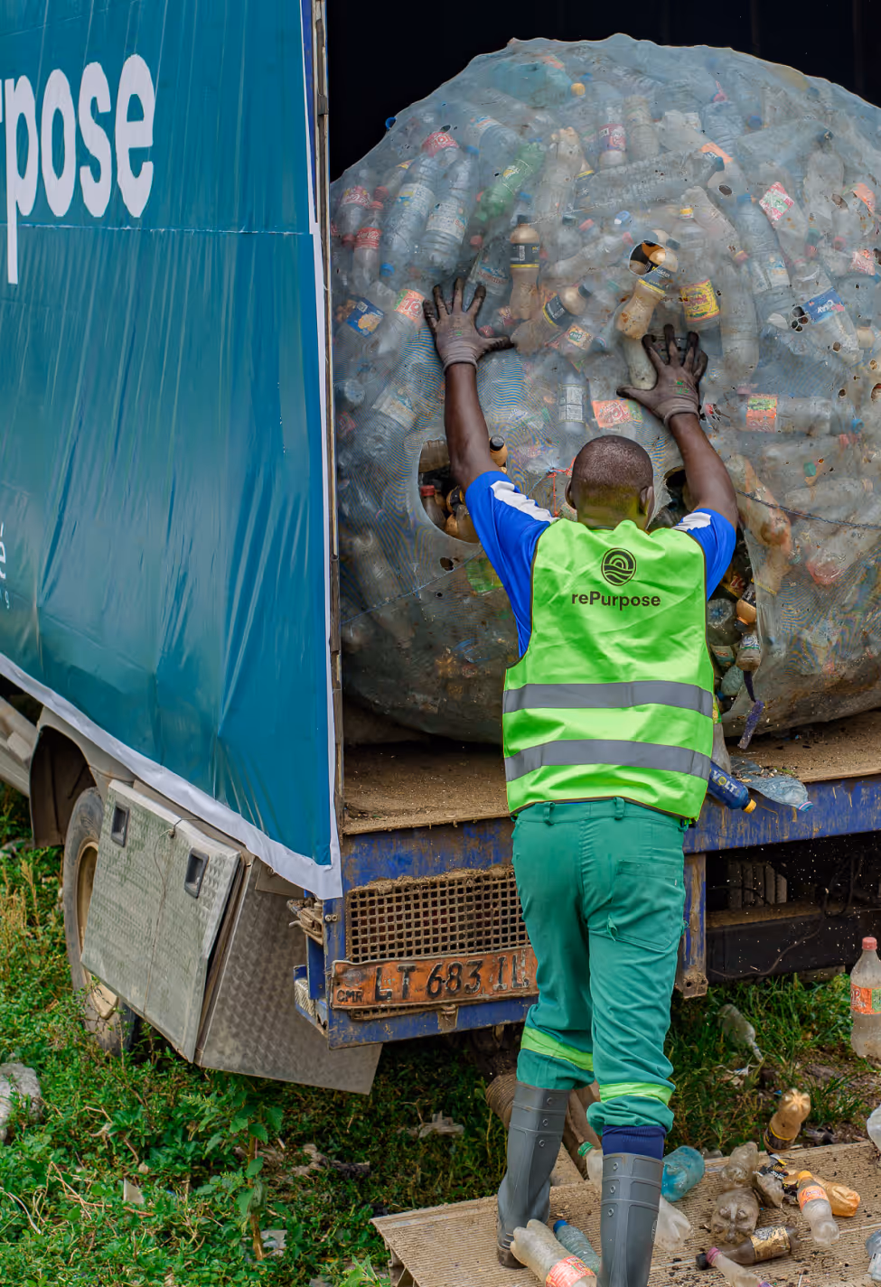 Waste worker loads a large bale of plastic bottles onto a recycling transport truck.
